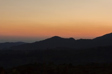 The sun rises behind the mountain in the morning.