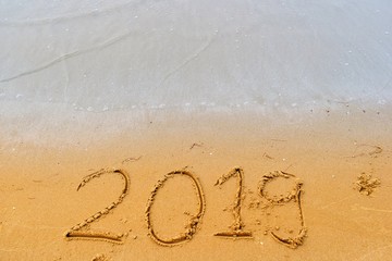 Happy new year concept, 2019 writing on sand beach.