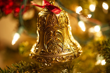 An ornate gold bell on a lite Christmas tree.