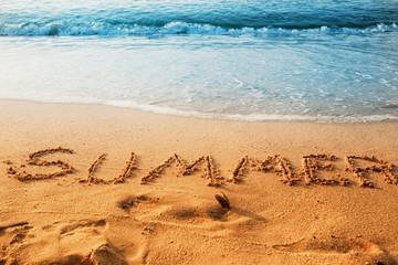 The word of summer writing on sand beach with waves blue ocean.