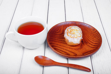 A cup of tea and sweet donut on wooden plate over  wooden tabletop with wooden  spoon. Celebration concept