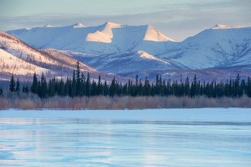 Snowy mountains in the rays of dawn. Winter landscape with the mountains and the frozen lake in...