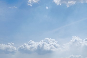Blue sky background with puffy white clouds and sunlight.