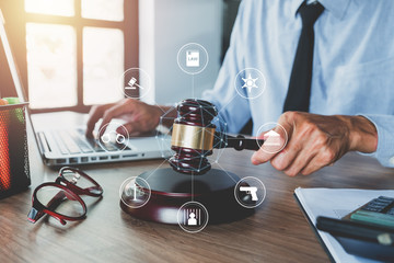 Male judge working with laptop computer, legal books and gavel on white wooden table in courtroom.justice and law concept with virtual interface icons network diagram.
