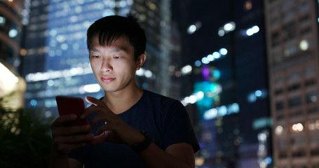 Man use of mobile phone in city at night
