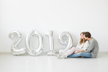 New year, celebration and holidays concept - love couple with sign 2019 made of silver balloons for new year on white background