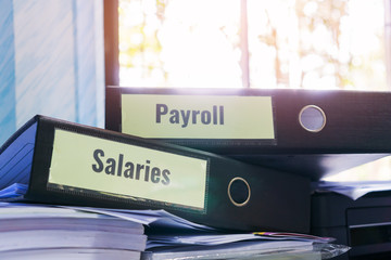 Payroll and salaries folders stack with label on black binder on paperwork documents summary...