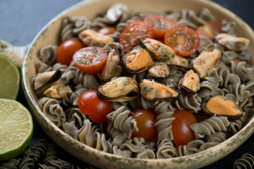 Close-up of fusilli made of hemp flour and served with tomatoes and mussels, studio shot