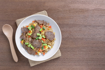 top view of fried rice with beef in a ceramic dish on wooden table. asian homemade style food concept.