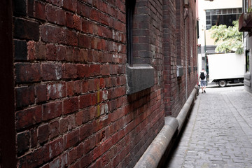Abstract style photograph looking down a brick lined alley way with cobblestones