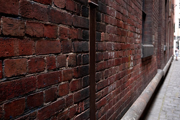 Abstract style photograph looking down a brick lined alley way with cobblestones