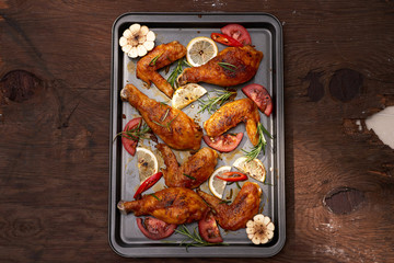 Roasted chicken wings on baking tray over dark wooden background with copy space. Top view, flat lay