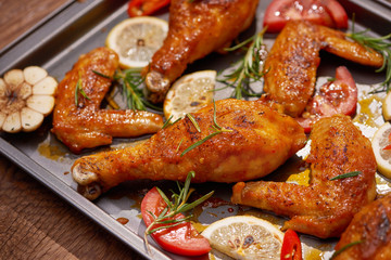 Roasted chicken wings on baking tray over dark wooden background with copy space. Top view, flat lay