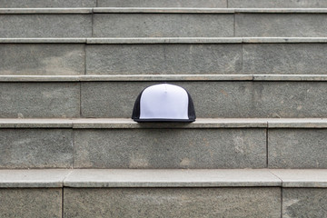 Mesh cap black white color in outdoor. Trucker hat black white in stairs.