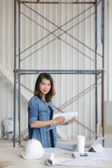 Beautiful Asian engineer woman in blue jeans shirt standing and writing