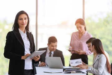 Graceful business woman in black suit standing with dignified manner in office