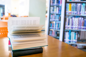 Learning concept with opening book in library, isle of bookshelves in school study class room background.