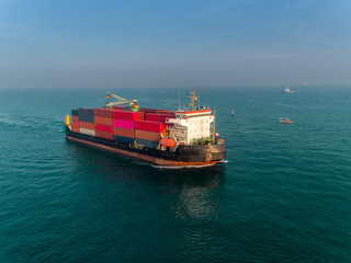 Fototapeta premium Container ship on the sea port and working crane bridge load full of container for logistics import export, shipping or transportation.