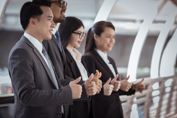 Group of business people with businessman leader on the cityscape show hands's like for victory after successful project. Human resources concept. Soft focus and blur. Bright warm tone.