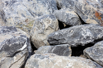 Boulders stacked on top of one another beside an industrial port.