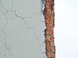 ruined concrete wall with cracks and fragments of red brick
