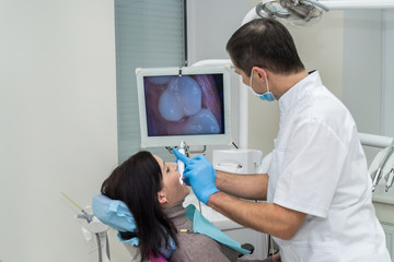Dentist checking patient's teeth with camera in stomatology