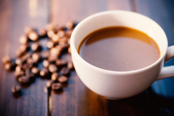 Cup of coffee and roasted coffee beans on wooden table, hot drink