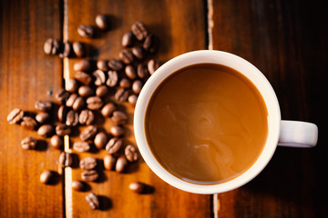 Cup of coffee and roasted coffee beans on wooden table, hot drink