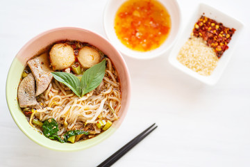 Spicy rice noodles soup in a bowl with chopsticks and ingredients, Thai food