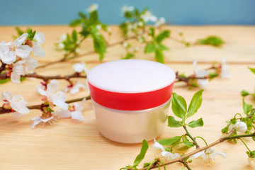 jar of cream and a branch with apricot flowers