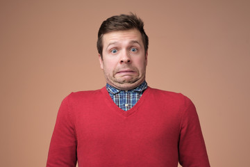 Funny caucasian man grimacing guilty face at studio background