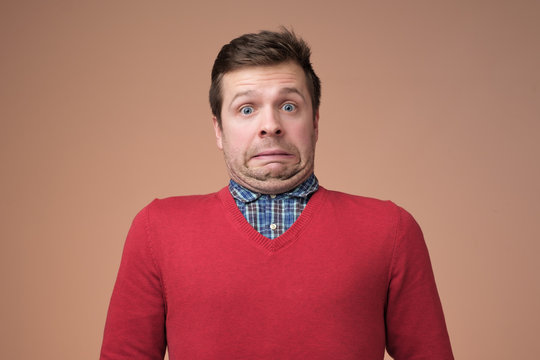 Funny caucasian man grimacing guilty face at studio background