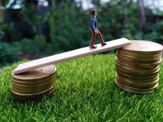 miniature figure young bussinesman keep trying to get higher income walking at stack of coin at...
