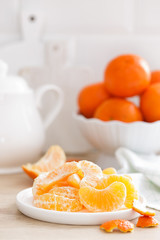 Fototapeta na wymiar Tangerines. Sweet tasty peeled tangerines on plate on white kitchen background closeup. Healthy and delicious vegan, vegetarian food.
