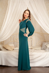 charming girl in a beautiful evening long dress on the background of a canopy bed in her bedroom © goldeneden