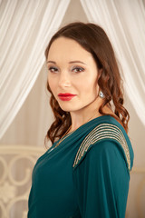 charming girl in a beautiful evening long dress on the background of a canopy bed in her bedroom © goldeneden