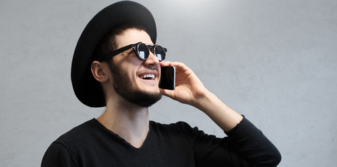 Happy hipster man with sunglasses caling on smartphone.