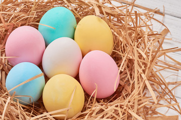Fototapeta na wymiar Easter background. Colorful easter eggs in paper nest on a white background, close up