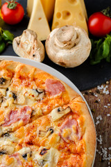 Italian pizza with ingredients on a wooden background, close up