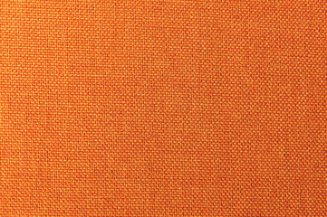 Textured background surface of textile upholstery furniture close-up. Orange color fabric structure