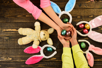 Father and kid painting Easter eggs - top view. Rabbit's family with bunny ears. Egg surprise toys.