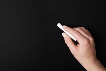 female hand hand writing with chalk on blank chalkboard background with copy space