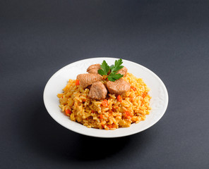 Fragrant Pilau. Pilaf, fried rice with meat and vegetables on a white plate. Isolated on gray.