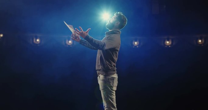Medium shot of an actor performing a monologue in a theater while holding his script