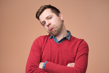 Sad young man in red sweater is exhausted with work or tired of listening his wife chatting.