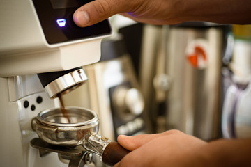 Just push the button. Fresh ground coffee in portafilter. Barista grind coffee beans using coffee machine. Coffee grinder grinding roasted beans into powder. Barista makes espresso in cafe