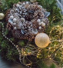 Festive handmade wreath with pine cones, Christmas decoration, ribbons and fir branches on a dark background