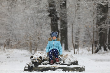 girl child in a winter park and bear sculpture