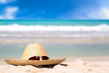 Beach accessories on sand for summer vacation concept. Straw hat with sunglasses on white sand...