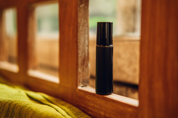 Essential oils roll on perfume in a dark brown glass bottle among nature background. Beauty...